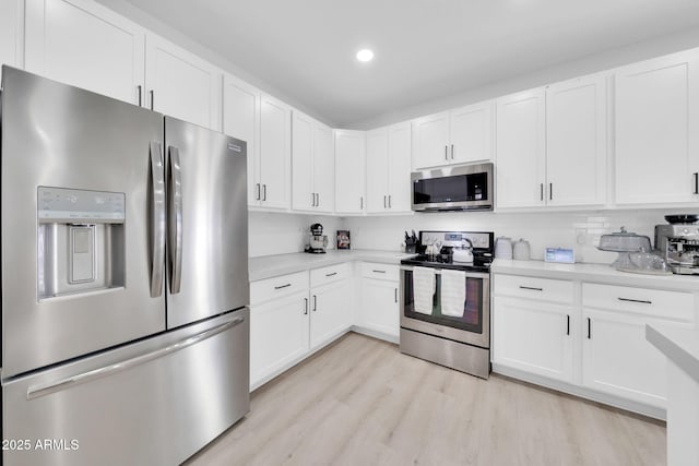 3034 N 39th St Unit 12, Phoenix, AZ 85018 - kitchen featuring appliances with stainless steel finishes, light countertops, white cabinets, light wood-style flooring, and recessed lighting