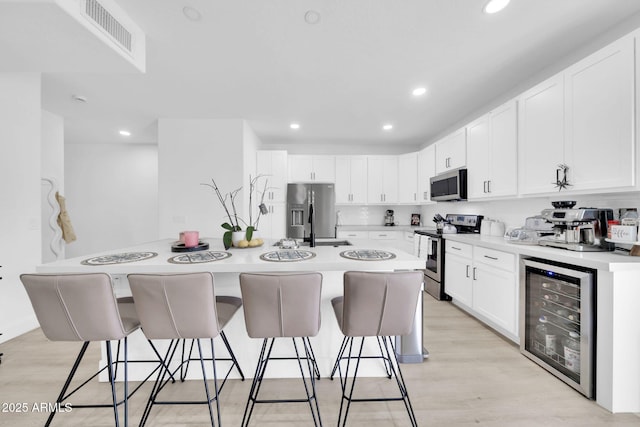 3034 N 39th St Unit 12, Phoenix, AZ 85018 - kitchen featuring beverage cooler, appliances with stainless steel finishes, a kitchen bar, white cabinets, and recessed lighting