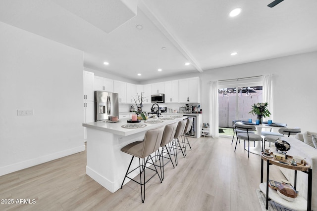 3034 N 39th St Unit 12, Phoenix, AZ 85018 - kitchen featuring stainless steel appliances, a breakfast bar area, light wood-style flooring, recessed lighting, and light countertops