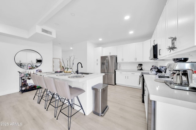 3034 N 39th St Unit 12, Phoenix, AZ 85018 - kitchen with stainless steel appliances, light wood finished floors, a breakfast bar, light countertops, and recessed lighting