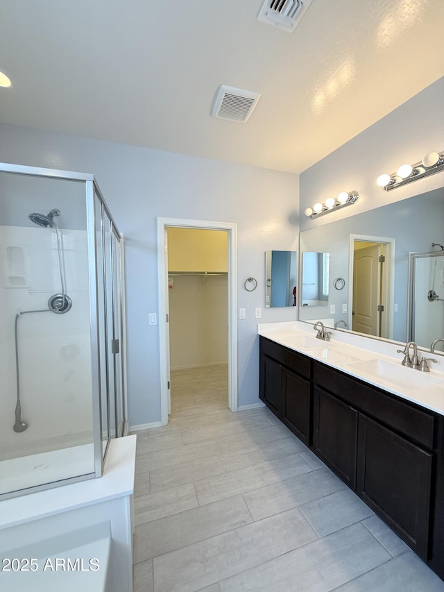 1241 E Palo Verde Dr, Casa Grande, AZ 85122 - bathroom featuring a shower stall, double vanity, a walk in closet, wood finished floors, and baseboards