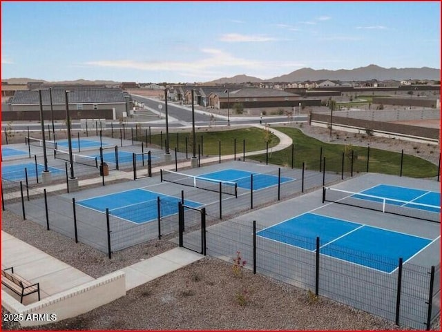 view of tennis court featuring a mountain view and fence