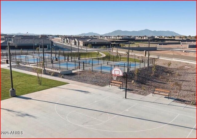 community pool with fence, community basketball court, a mountain view, and a yard