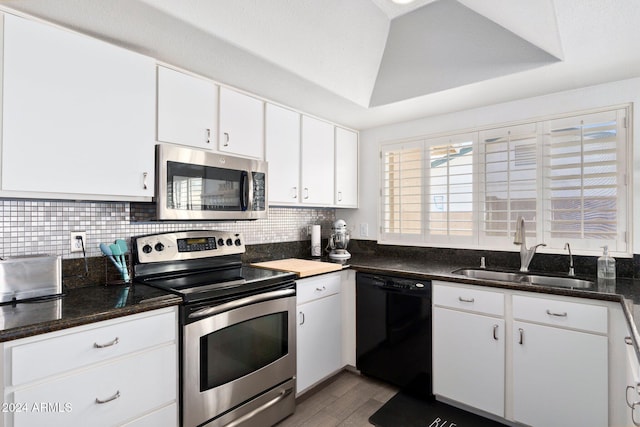 kitchen featuring light hardwood / wood-style floors, sink, appliances with stainless steel finishes, dark stone countertops, and white cabinets