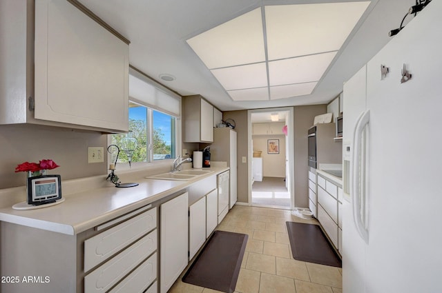 kitchen featuring white cabinetry, sink, light tile patterned flooring, and white appliances