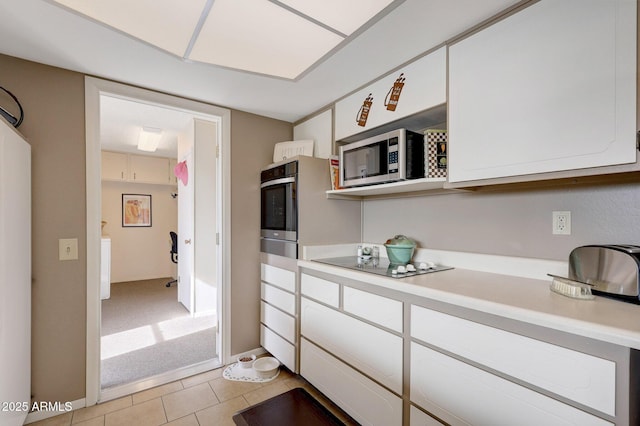 kitchen featuring light tile patterned flooring, white cabinets, and stainless steel appliances