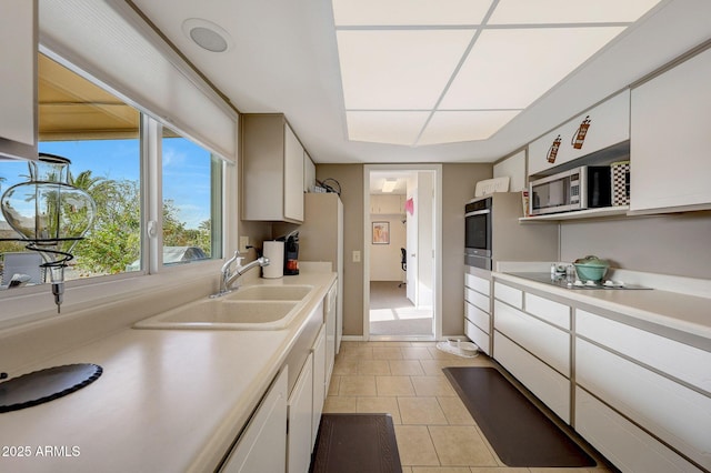 kitchen featuring white cabinets, appliances with stainless steel finishes, light tile patterned floors, and sink