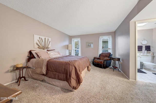 bedroom with connected bathroom, light carpet, and a textured ceiling