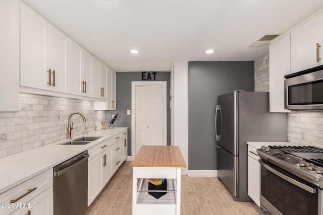 kitchen with a sink, stainless steel appliances, visible vents, and light wood-style flooring