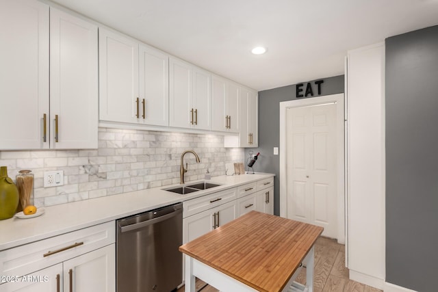 kitchen with a sink, white cabinetry, light countertops, and stainless steel dishwasher