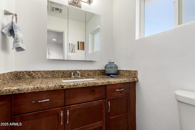 half bathroom featuring visible vents, toilet, and vanity