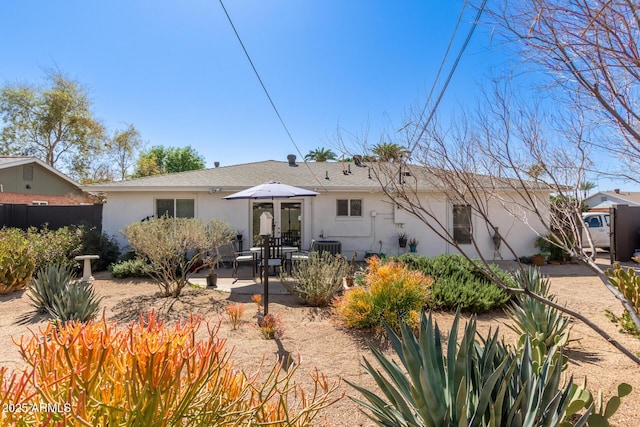 view of front of house with a patio area, stucco siding, and fence