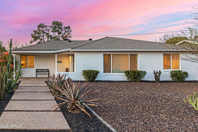 back of property with a shingled roof, a porch, and stucco siding