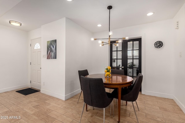 dining space featuring baseboards, plenty of natural light, a chandelier, and light wood finished floors