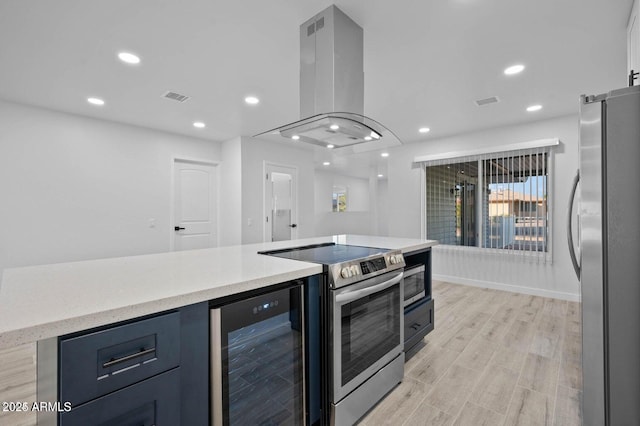 kitchen with island exhaust hood, light hardwood / wood-style flooring, beverage cooler, and appliances with stainless steel finishes