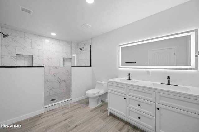 bathroom with a tile shower, vanity, and toilet