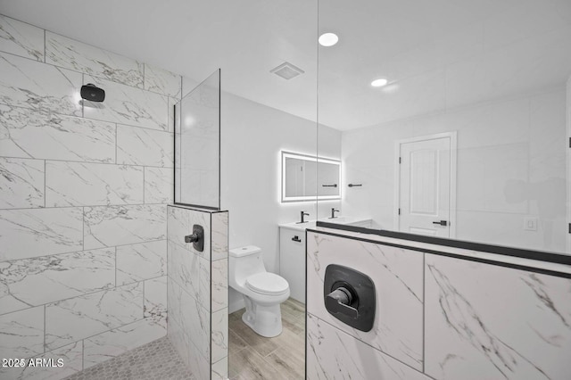 bathroom featuring tiled shower, vanity, and toilet