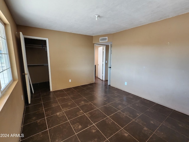 unfurnished bedroom with a walk in closet, dark tile patterned floors, and a closet