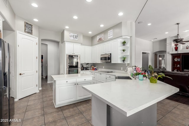 kitchen with sink, white cabinetry, stainless steel appliances, a center island, and kitchen peninsula