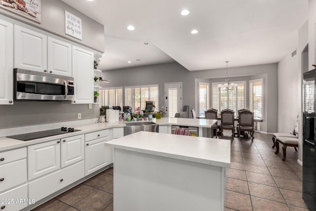 kitchen with sink, hanging light fixtures, appliances with stainless steel finishes, kitchen peninsula, and white cabinets