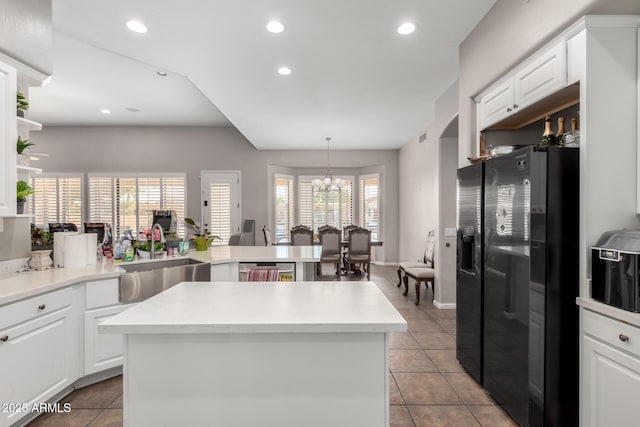 kitchen featuring a kitchen island, decorative light fixtures, sink, white cabinets, and fridge with ice dispenser