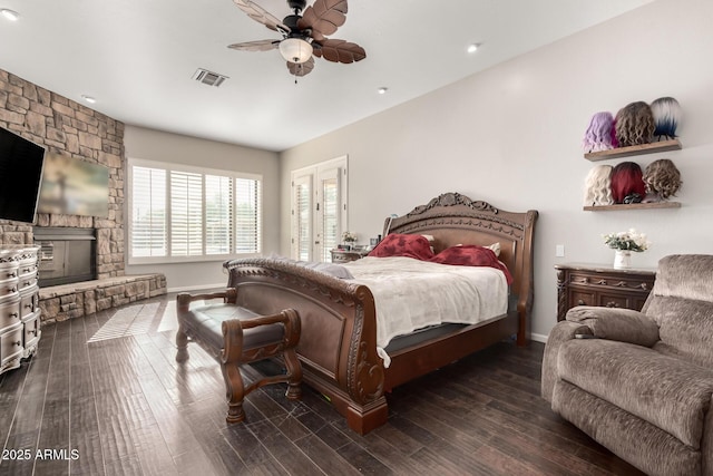 bedroom featuring a fireplace, dark wood-type flooring, and ceiling fan