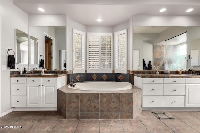 bathroom with vanity, tiled tub, and tile patterned flooring