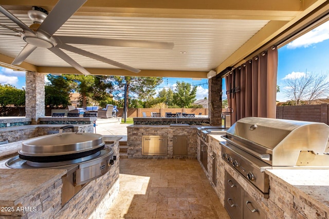 view of patio with an outdoor kitchen, area for grilling, and ceiling fan