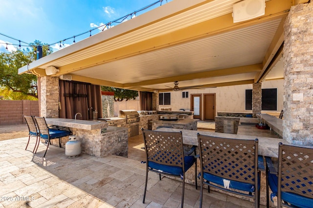 view of patio with an outdoor wet bar, grilling area, ceiling fan, and exterior kitchen