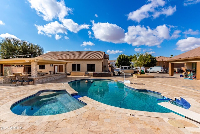 view of pool with a patio, an outdoor bar, and an in ground hot tub