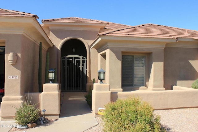 entrance to property featuring a tiled roof and stucco siding