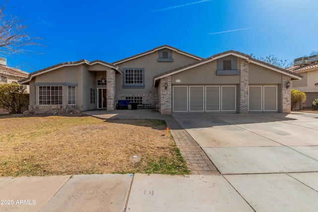 view of front of home with concrete driveway, brick siding, an attached garage, and stucco siding