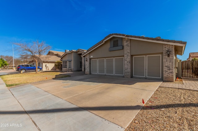 view of front of home with a garage, concrete driveway, stucco siding, fence, and brick siding