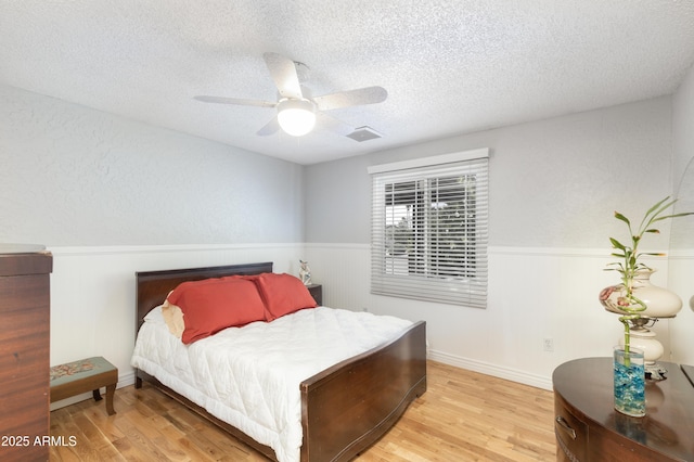 1445 W Wood Dr, Phoenix, AZ 85029 - bedroom featuring wainscoting, a textured ceiling, light wood-type flooring, and ceiling fan