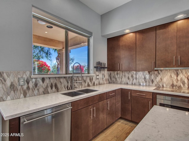 kitchen featuring sink, light stone counters, stainless steel dishwasher, oven, and backsplash