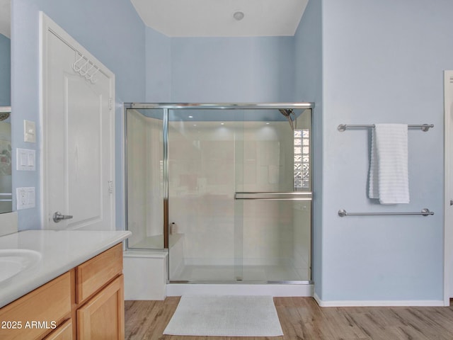 bathroom with walk in shower, vanity, and hardwood / wood-style flooring