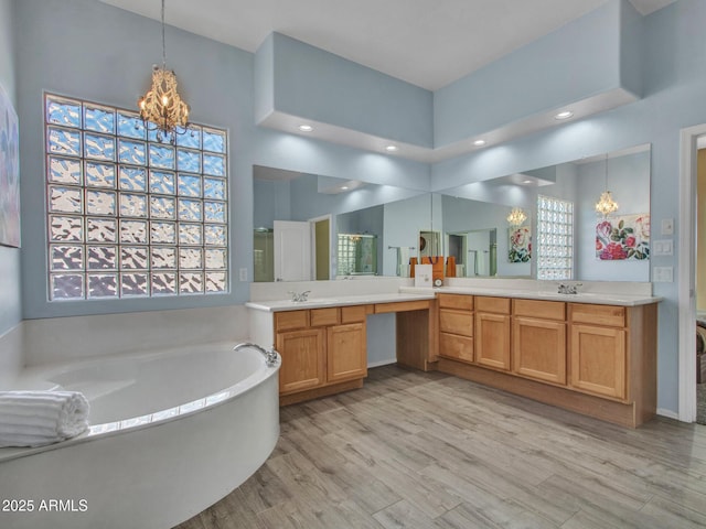 bathroom with a washtub, hardwood / wood-style floors, vanity, a wealth of natural light, and a chandelier