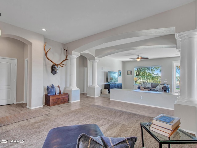 living room with decorative columns, ceiling fan, and light hardwood / wood-style floors