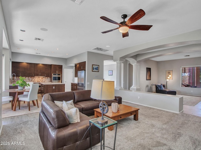 living room with ceiling fan, light colored carpet, and decorative columns