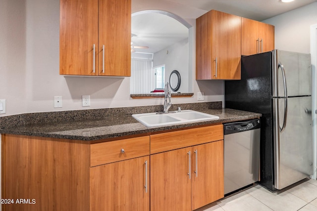 kitchen with light tile patterned flooring, appliances with stainless steel finishes, sink, and dark stone counters