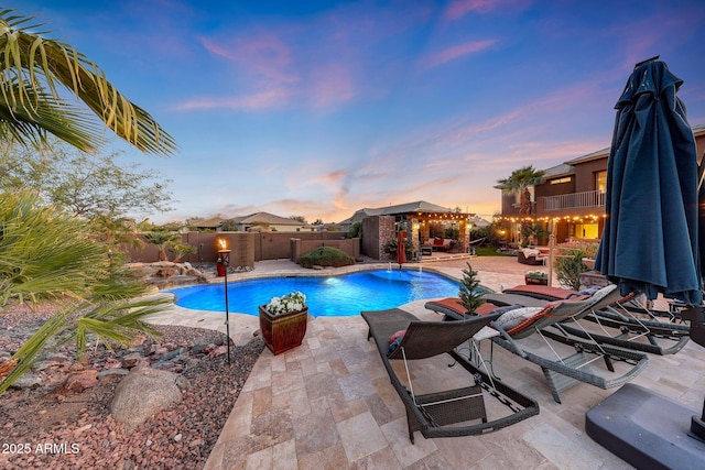 pool at dusk featuring a gazebo, pool water feature, and a patio