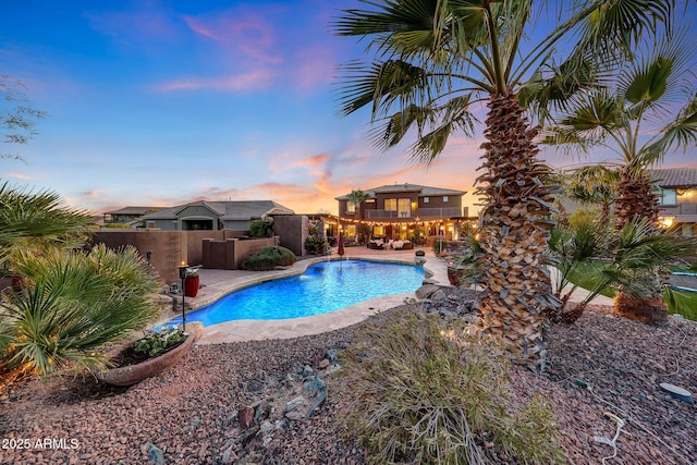 pool at dusk featuring a patio