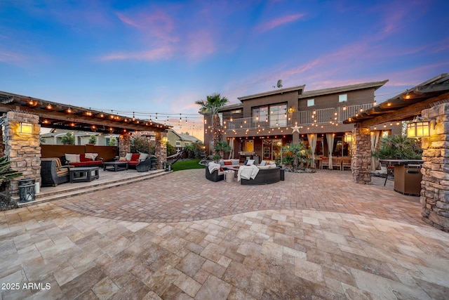 patio terrace at dusk with an outdoor living space with a fire pit