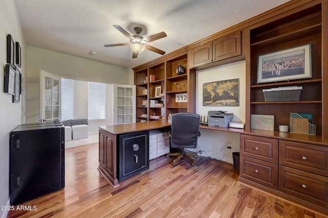 office area featuring built in desk, ceiling fan, and light wood-type flooring