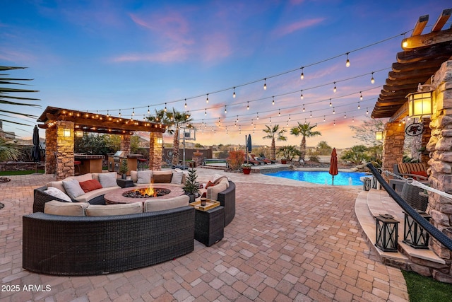 pool at dusk featuring area for grilling, an outdoor living space with a fire pit, and a patio