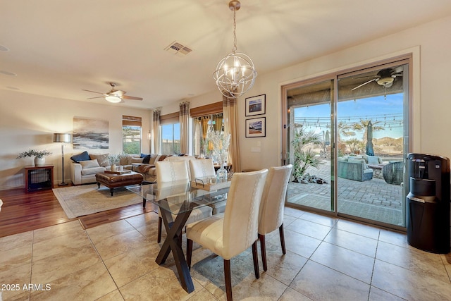 tiled dining room featuring ceiling fan with notable chandelier