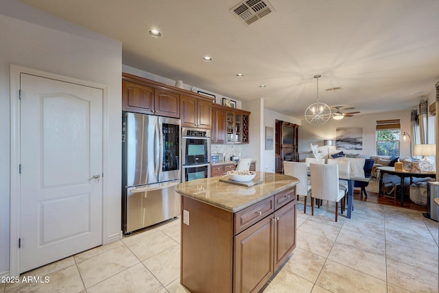 kitchen with stainless steel appliances, a center island, light tile patterned floors, and backsplash