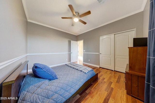 bedroom with ornamental molding, light hardwood / wood-style floors, a closet, and ceiling fan