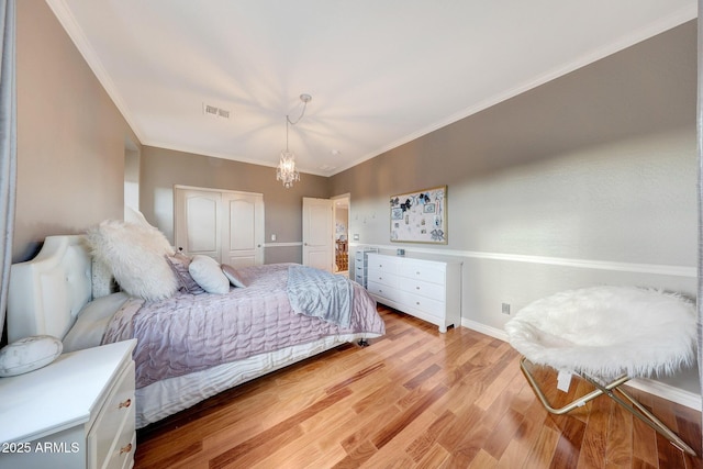 bedroom with a closet, ornamental molding, light hardwood / wood-style flooring, and a notable chandelier