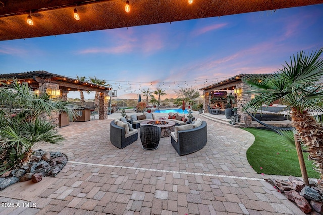 patio terrace at dusk featuring an outdoor living space with a fireplace and exterior kitchen